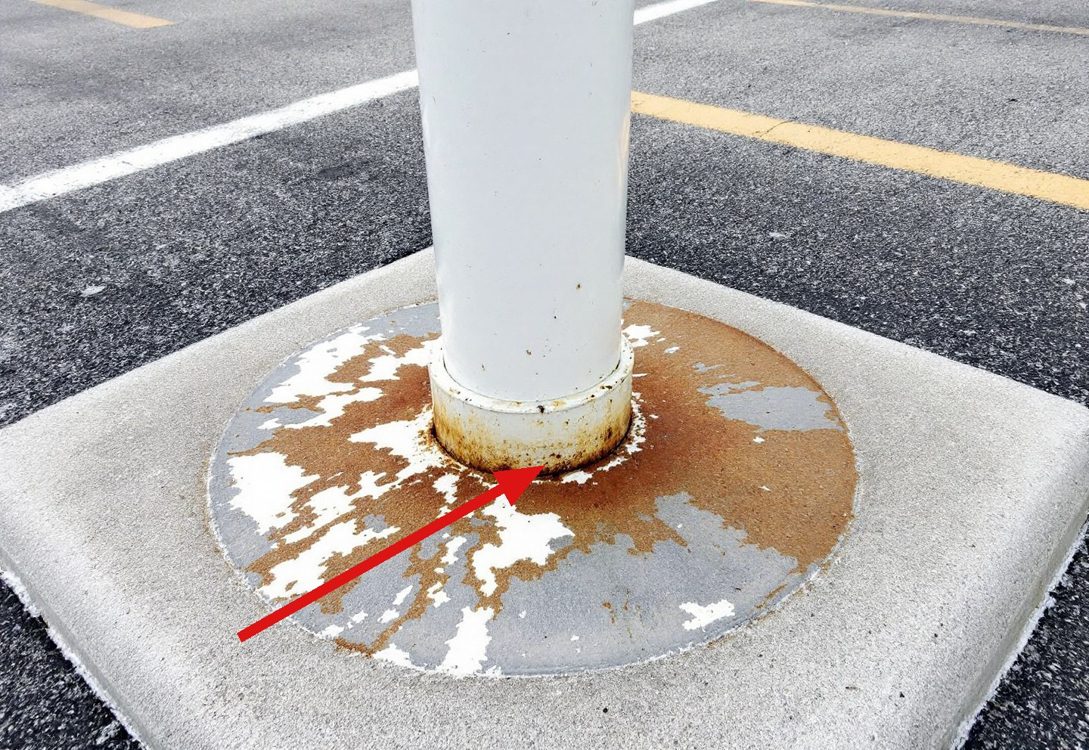 Illustration: steel bollard rusted at its base, a typical association compliance finding